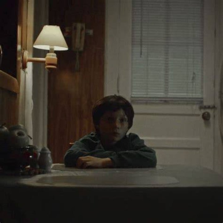 A young Skylar Gaertner sitting in front of his father with a Black + Decker drill case.