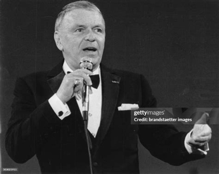 Frank Sinatra (1915-1998), US singer and actor, smiling while dressed in a grey jacket, a white shirt and a blue-and-white bow tie in a studio port...