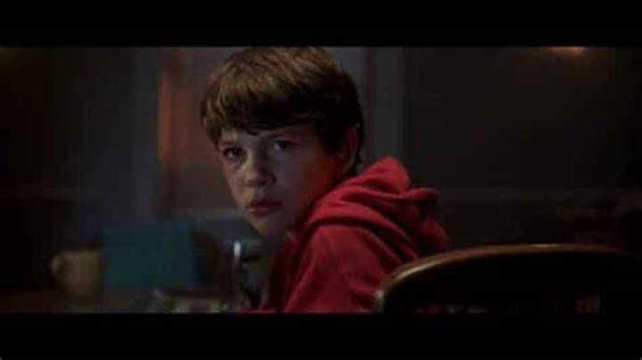 Gabriel Bateman looking left with a white V-neck T-shirt with red borders