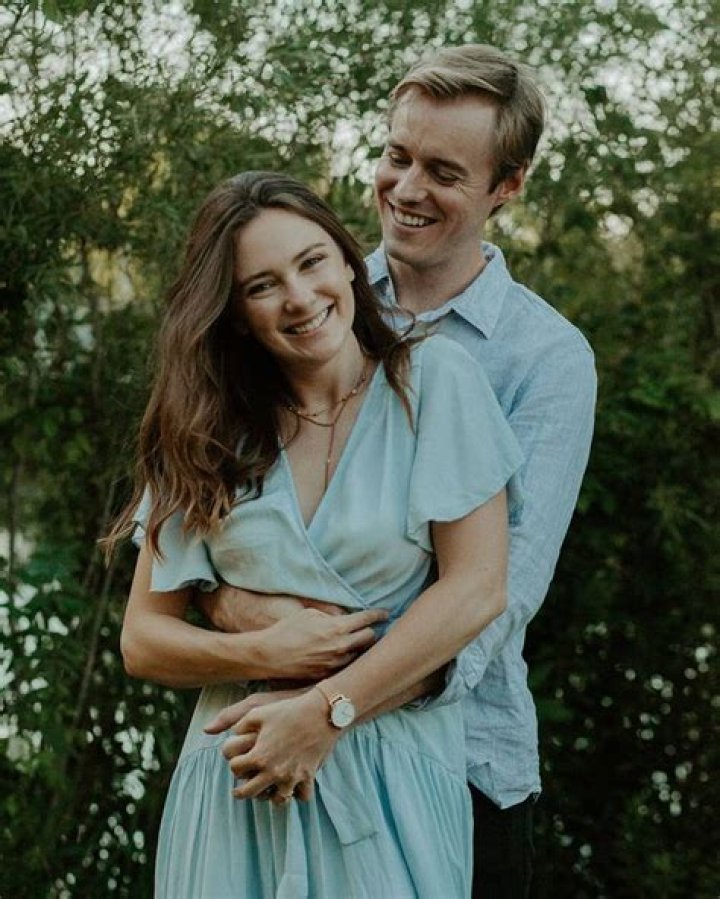 Samantha Munro posing with her husband by wearing blue one piece.